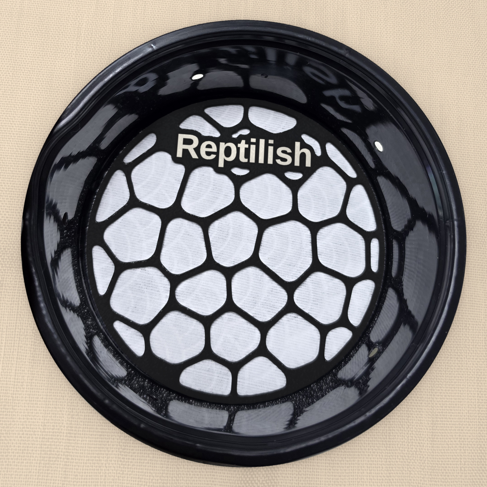 Okrągła płytka Pebble Plate w kolorze Carbon Black z grawerem, leżąca na macie w okrągłym pojemniku
