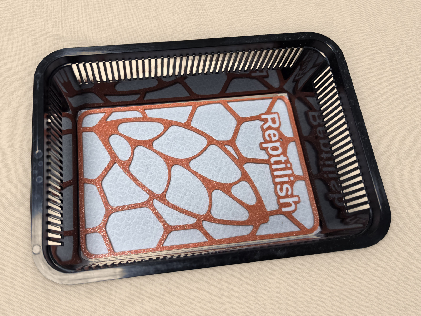 Prostokątna płytka Pebble Plate w kolorze Terracotta z grawerem, leżąca na macie w małym faunarium